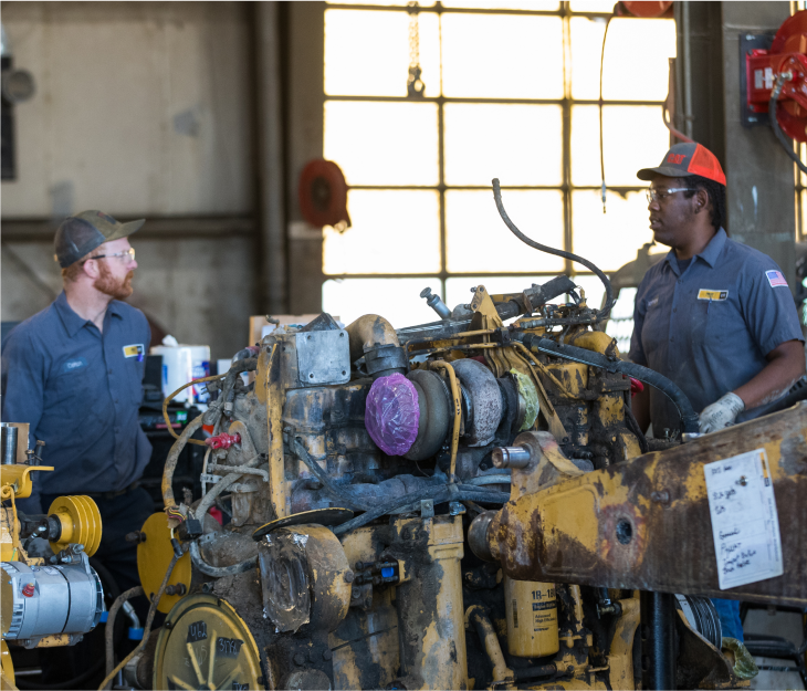 Two male Foley employees work together on a large piece of equipment.