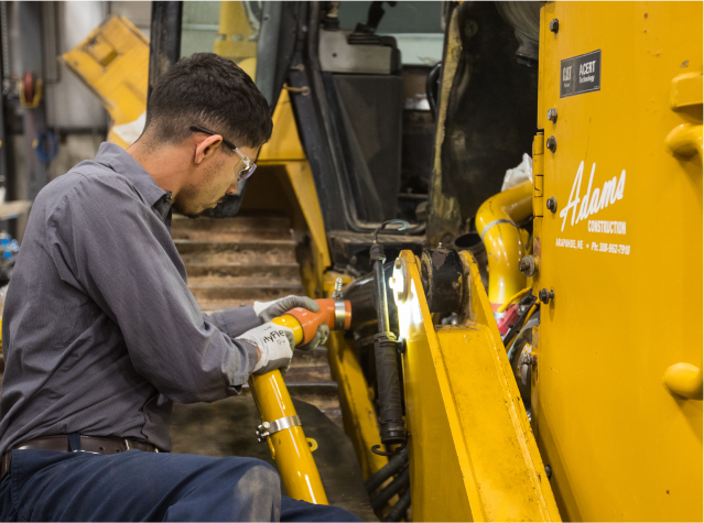A Foley employee working on Caterpillar equipment wearing safety glasses and protective gloves.