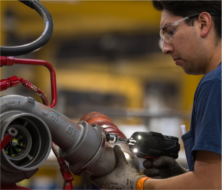 Promise-Act A Foley employee working on Caterpillar equipment wearing safety glasses and protective gloves.