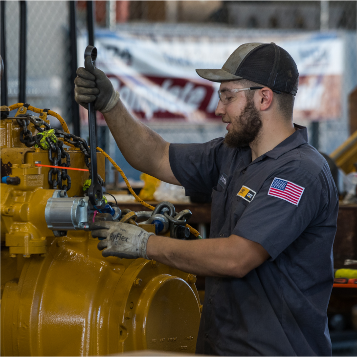 A Foley employee who is a Veteran works on a large piece of equipment while wearing safety glasses.