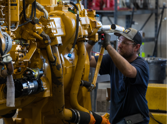 Close-up of a Foley employee working on a machine wearing safety glasses and protective gloves.