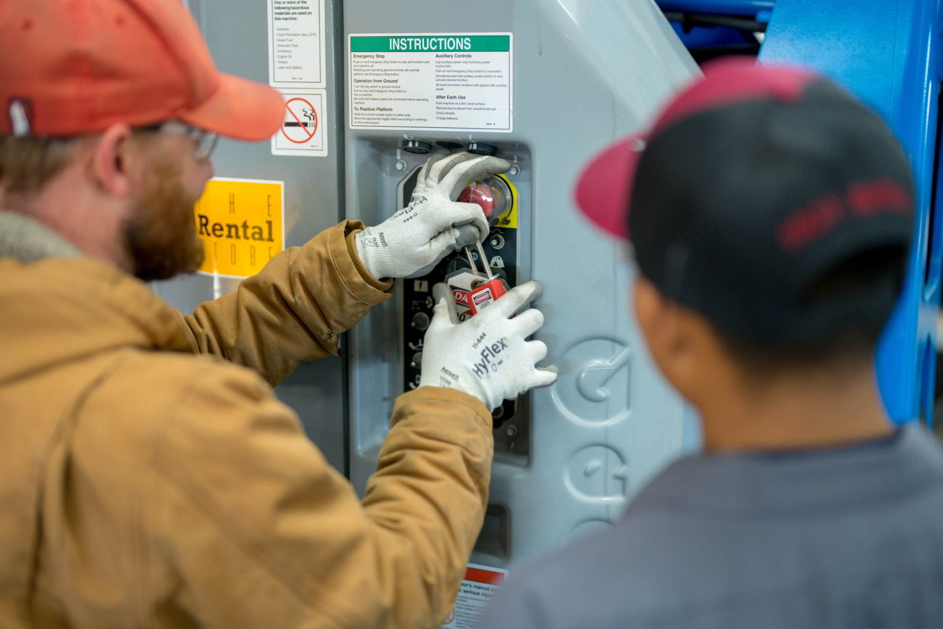 Two service technicians safely perform lockout-tagout on a machine.